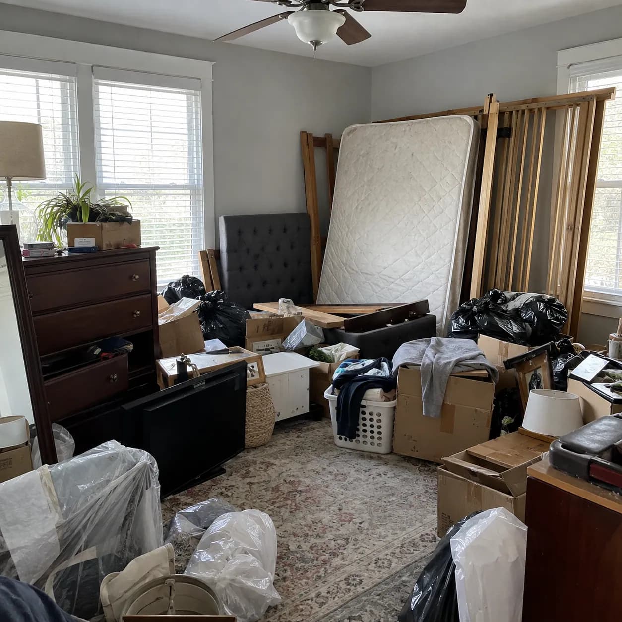 A Fort Worth bedroom stacked with a mattress, dressers, bagged clothing and boxes before a cleanout