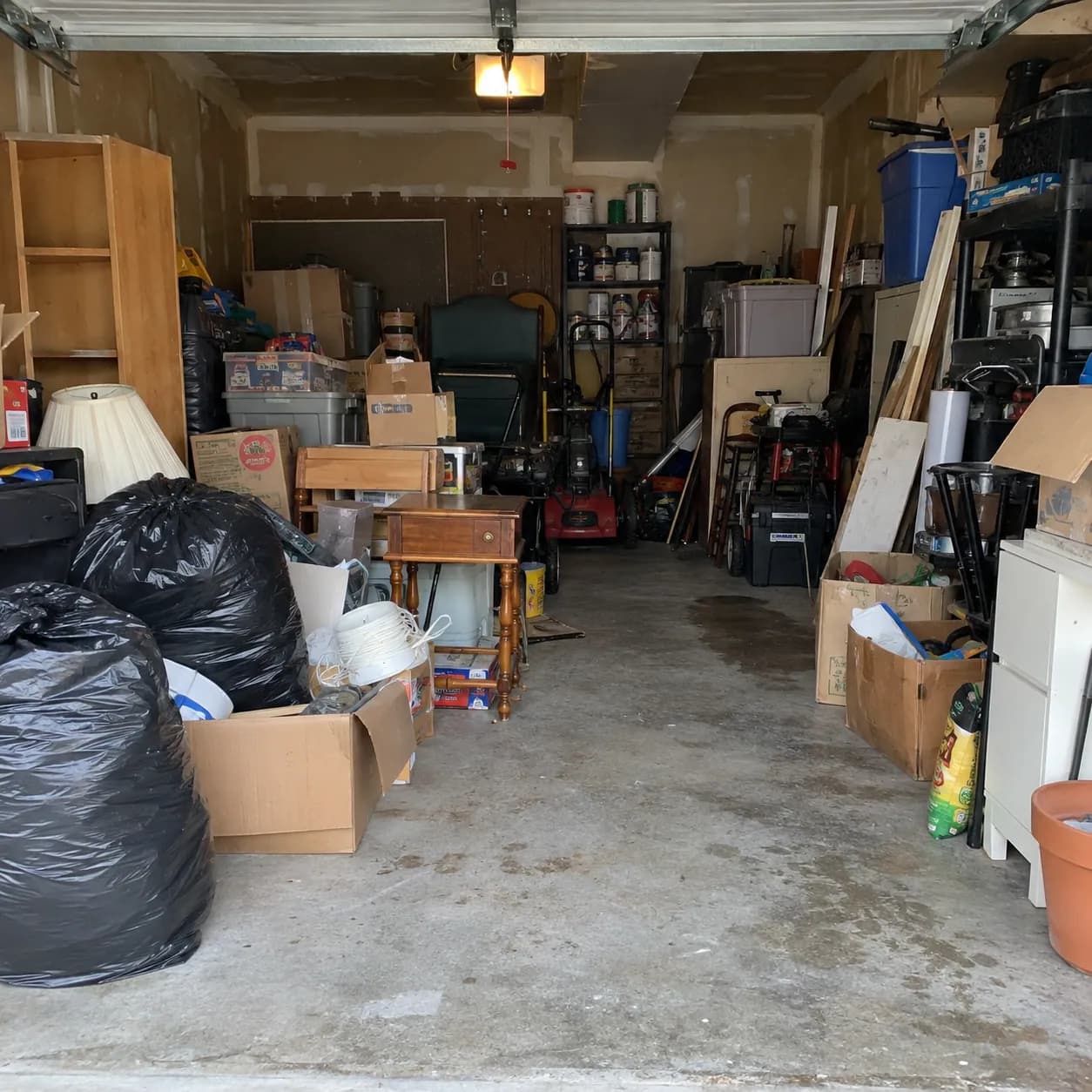A two-car garage filled with boxes, storage bins, tools and bagged clutter along both walls